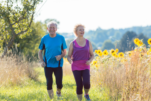 cheerful senior couple jogging together outdoors