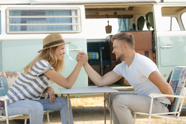 happy young couple armwrestling on camping