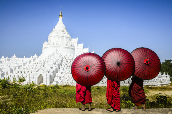 asian monks under umbrellas viewing historic