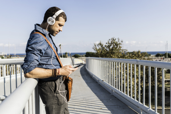 man standing on footbridge listening music