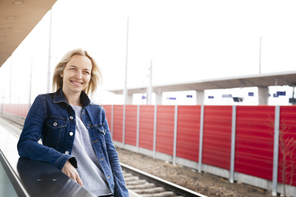 smiling woman waiting at station platform