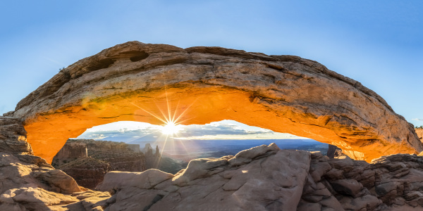 the sun rising under mesa arch