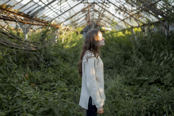 young woman in abandoned greenhouse
