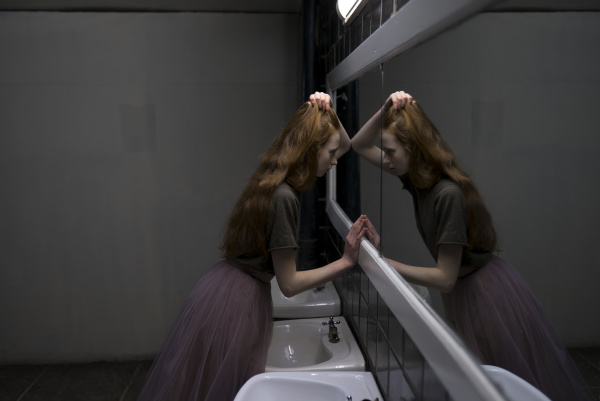 young woman leaning on bathroom mirror
