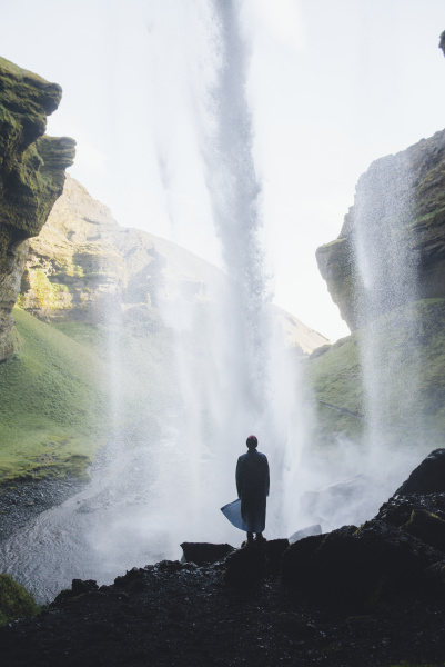 silhouette of man behind kvernufoss waterfall