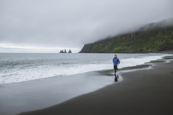 man jogging on beach in vik