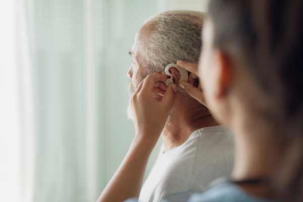 healthcare worker putting hearing aid
