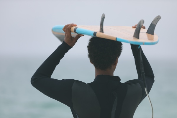 male surfer carrying surfboard on her