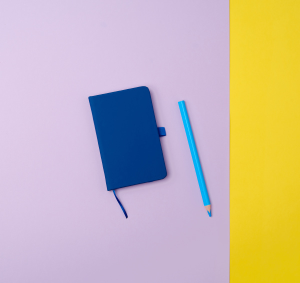 closed notebook and wooden blue pencil