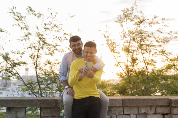 gay couple using cell phone outdoors