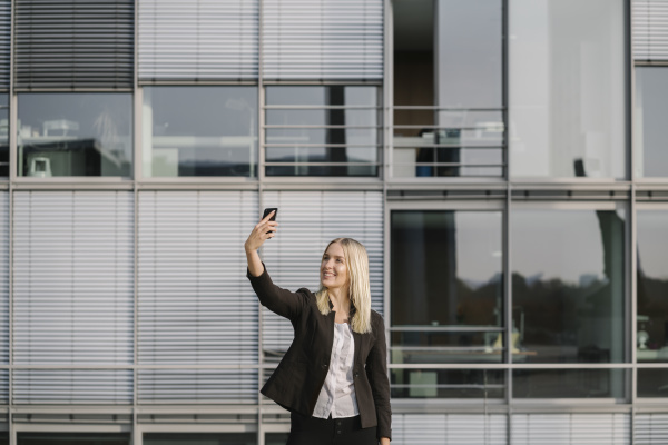 blond businesswoman using smartphone and taking