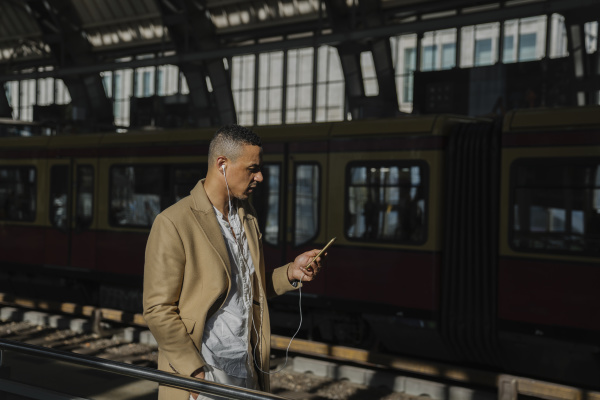 man standing at train station using