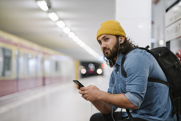 man with backpack listening music with
