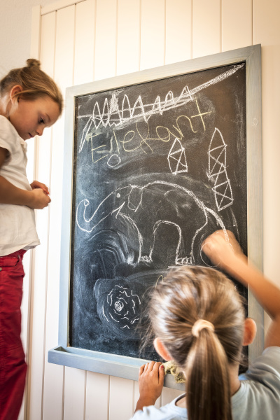 two girls drawing on blackboard
