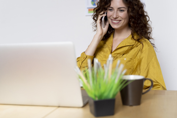 smiling woman using laptop and smartphone