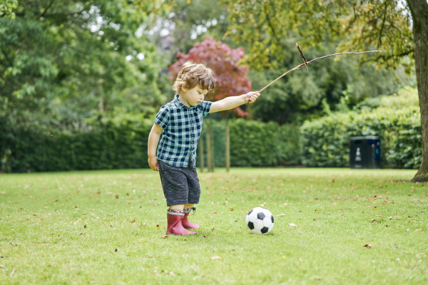 toddler playing with stick and football