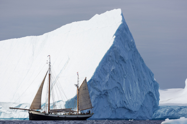 ship sailing below majestic iceberg atlantic