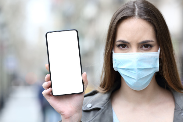 woman with protective mask showing phone
