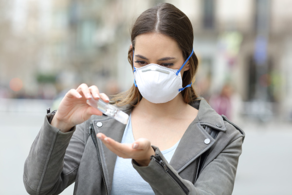 girl with mask applying hand sanitizer
