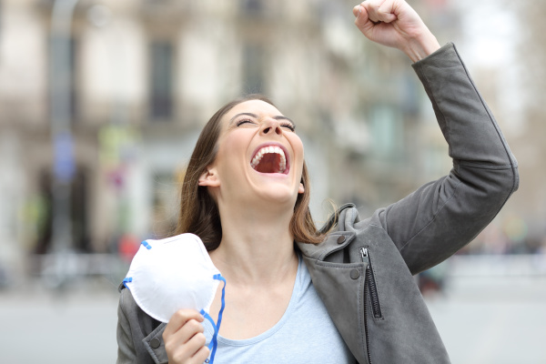 excited woman celebrating holding mask on