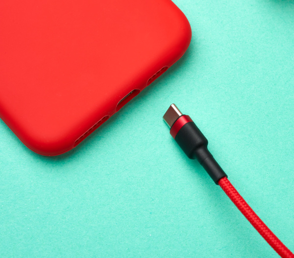 red smartphone and cable in textile