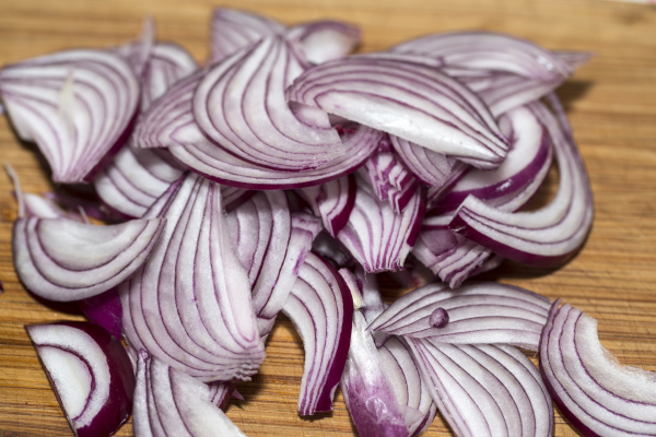 red onion slices on wooden board