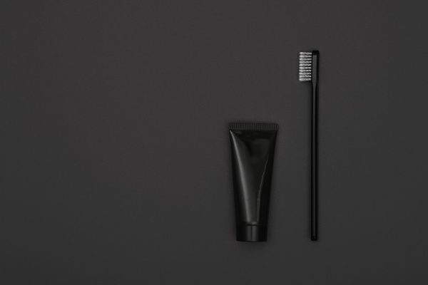 black toothpaste and toothbrush over grey