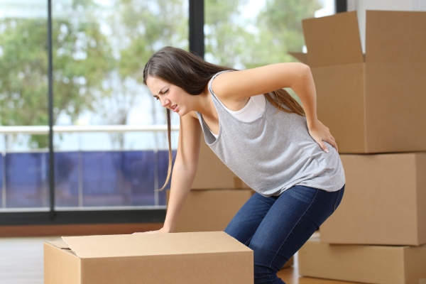 woman moving boxes suffering backache at