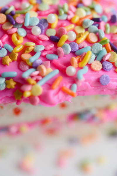 colorful sprinkles on pink cake frosting
