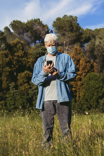 senior man with mask using smartphone