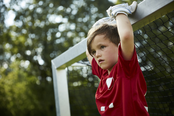 thoughtful soccer boy holding goal post
