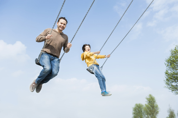 cheerful father and son swinging against