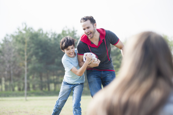 cheerful father and son playing rugby