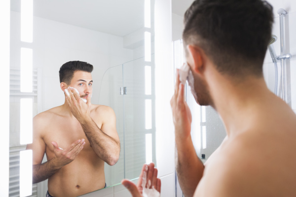 reflection of young man applying shaving