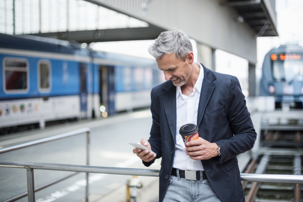 businessman holding coffee using smart phone