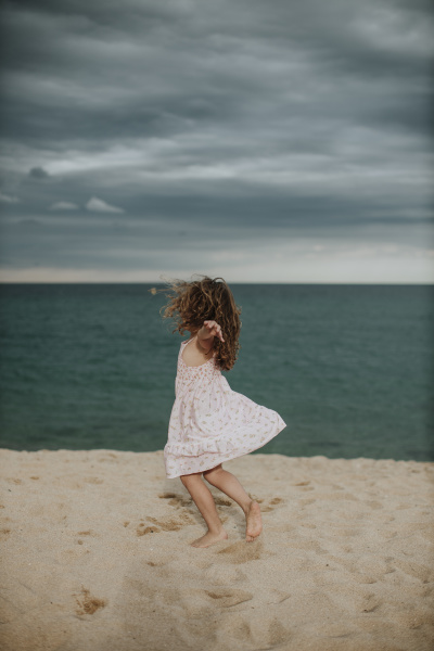 carefree girl dancing on sand against