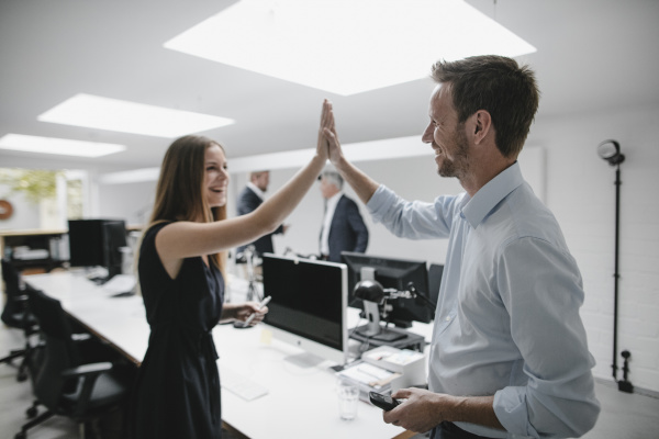 businesswoman and man highfiving in office
