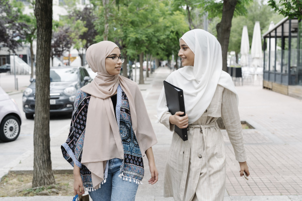 muslim sisters talking while walking on