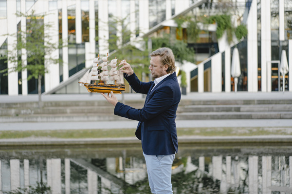 businessman holding model ship in the