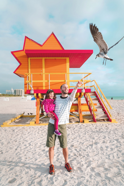 father carrying daughter feeding seagull while