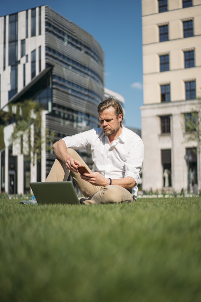 businessman with laptop sitting in grass