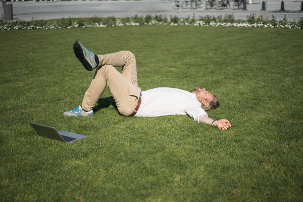 businessman lying in grass next to