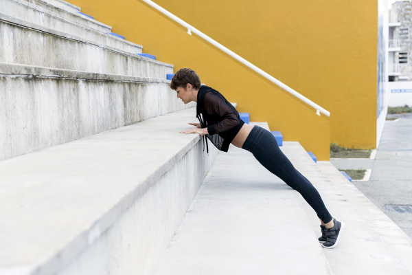 athletic woman exercising plank on stairs