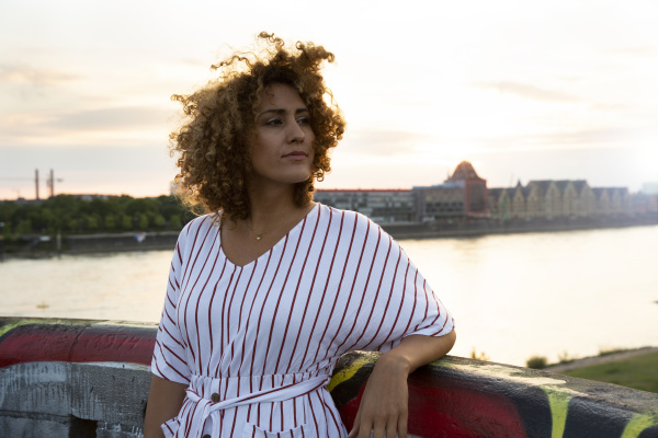 thoughtful woman with curly hair standing