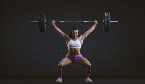 young woman practicing barbell squat at