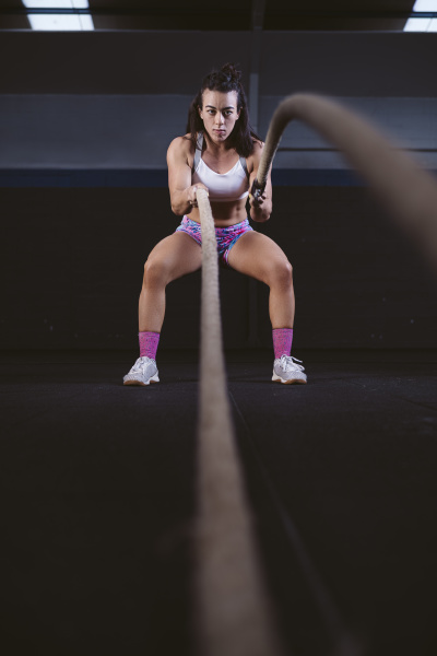 young woman exercising with battle ropes