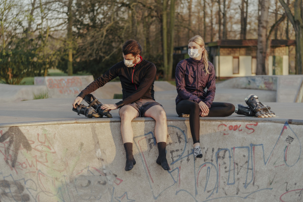 young couple sitting with inline skates