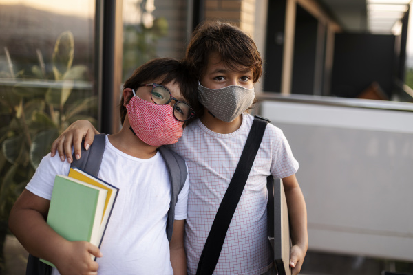 siblings with books wearing masks outdoors