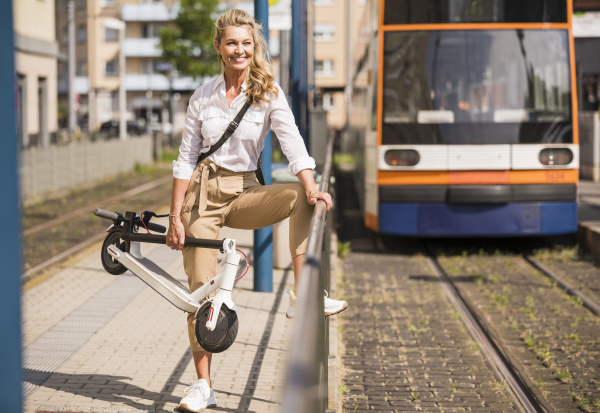smiling businesswoman carrying push scooter while