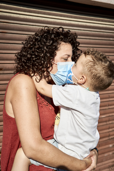 mother carrying son with masks kissing